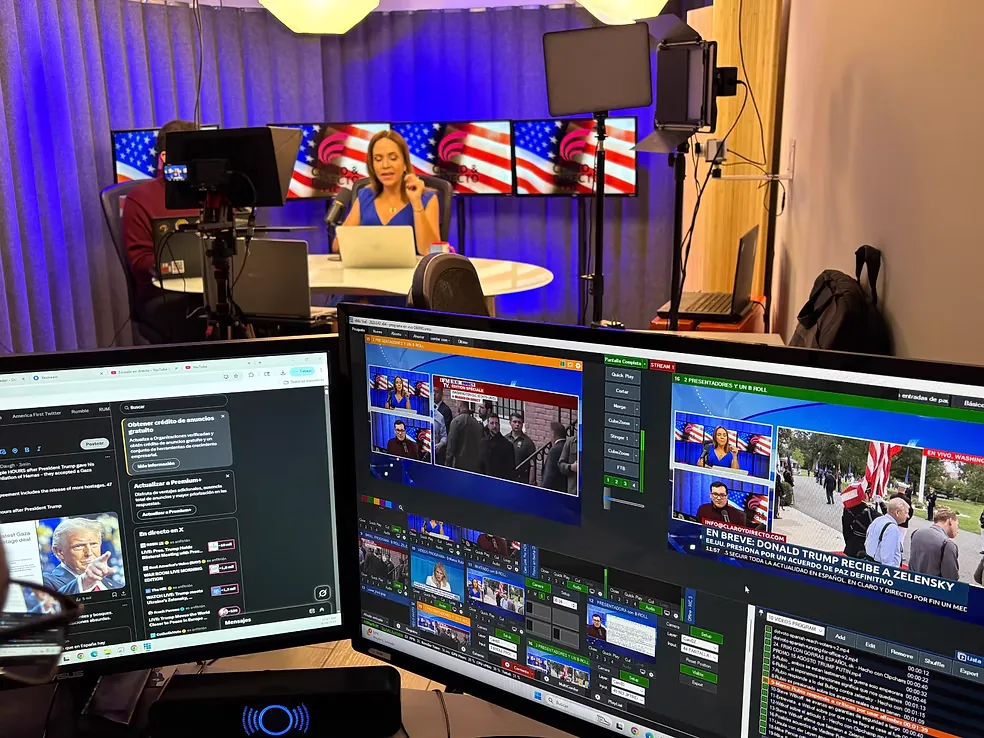 Set de podcast con mesa de conversación y pantallas, visto desde el control